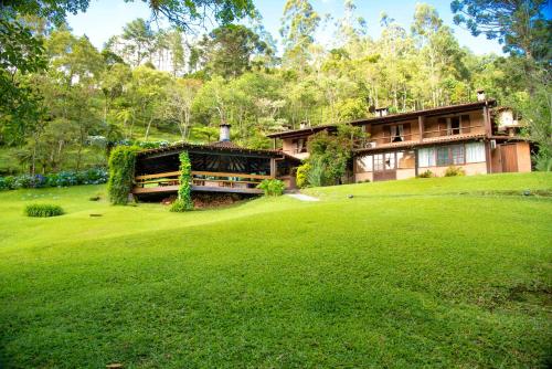 uma casa num campo verde exuberante em frente em Pousada Tijupá em Visconde de Mauá