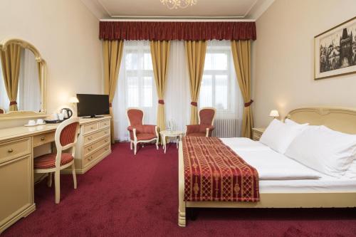 a hotel room with a bed and a desk and chairs at OREA Spa Hotel Palace Zvon Mariánské Lázně in Mariánské Lázně