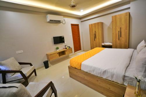 a bedroom with a bed and a chair and a tv at Hotel Ceasta, Beside US Consulate Hyderabad, Gachibowli in Gundipet