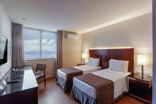 a hotel room with two beds and a flat screen tv at Orla Copacabana Hotel in Rio de Janeiro