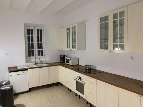 uma cozinha com armários brancos e um balcão de madeira em Gite tout confort - Vexin - Val d'Oise em Frémainville