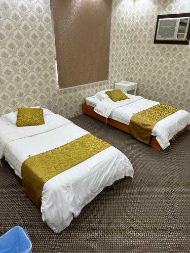 two beds sitting in a room with at فندق ادوماتو ADOMATo HOTEl in Dawmat al Jandal