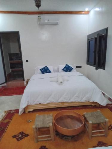 a bedroom with a large bed with a wooden table at Hotel AZUL Todra Gorges in Tinerhir