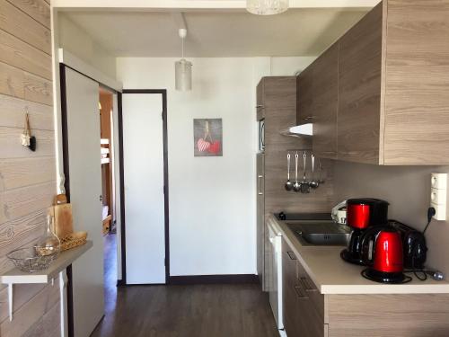 une cuisine avec des armoires en bois et un comptoir dans l'établissement Appartement confortable à La Plagne-Tarentaise 34 m² avec balcon, à La Plagne Tarentaise