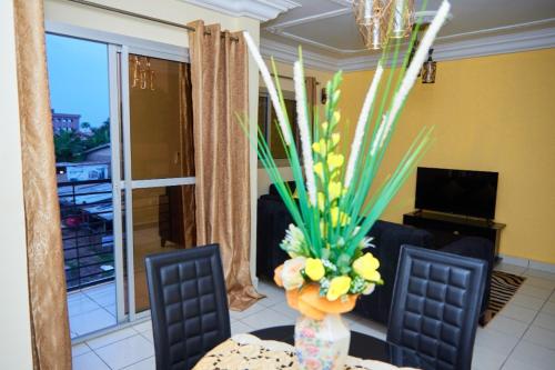 a living room with a table and a vase with flowers at LUXOR RESIDENCE YASSA DOUALA in Ngori