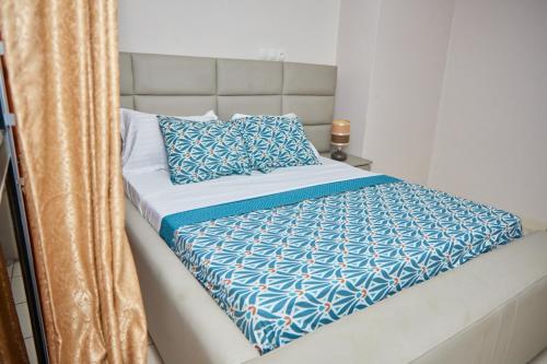 a bed with a blue and white comforter on it at LUXOR RESIDENCE YASSA DOUALA in Ngori