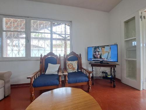uma sala de estar com 2 cadeiras e uma televisão de ecrã plano em 3 QTS Churrasqueira Garagem perto do Forte e Ilha do Japonês em Cabo Frio