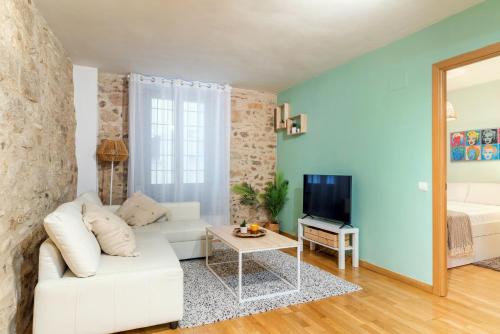 Una sala de estar con un sofá blanco y un televisor. en Elena Apartments - Girona, en Girona