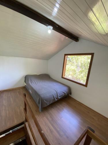 a bed in a small room with a window at Chalés paradise - Família in Serra do Cipo
