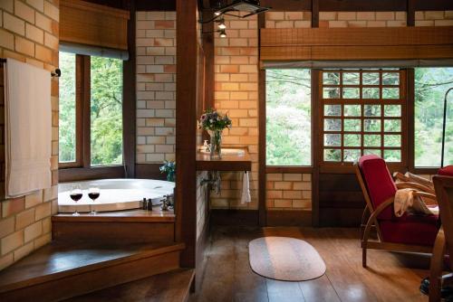 a bathroom with a tub in a room with windows at Pousada Tijupá in Visconde De Maua