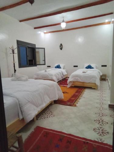 a bedroom with two beds and a mirror on the wall at Hotel AZUL Todra Gorges in Tinerhir