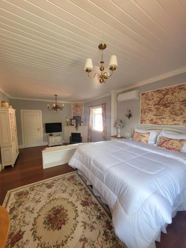 a bedroom with a large white bed and a chandelier at La Belle Provence in Itaipava