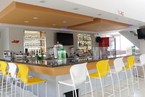 a bar with yellow and white chairs in a restaurant at Hotel Dibeni Pereira in Pereira