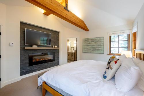 a bedroom with a fireplace with a tv on the wall at Newly renovated 4-bed, bath ski-in, ski-out with fireplaces, private hot tub, and private garage! in Whistler