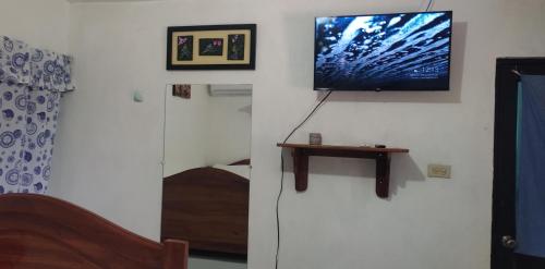 uma sala de estar com uma televisão na parede em Flor's House em San Cristóbal