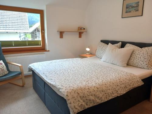 ein Schlafzimmer mit einem Bett, einem Fenster und einem Stuhl in der Unterkunft Apartments Markež in Bohinj