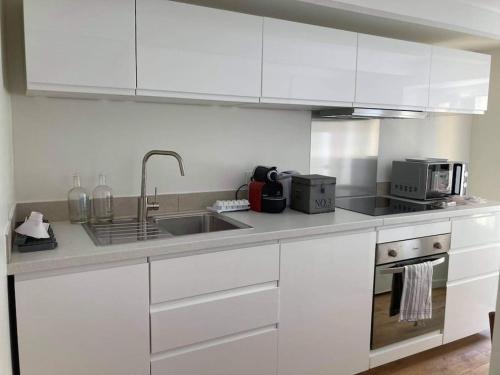 une cuisine avec des armoires blanches et un évier dans l'établissement Charmant studio Vauban, à Marseille
