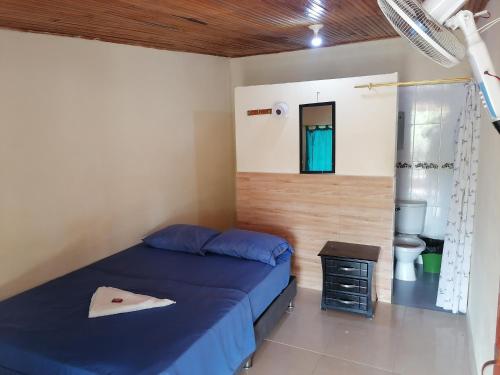 a bedroom with a blue bed and a toilet at Posada Turística Noches De Saturno in Villavieja