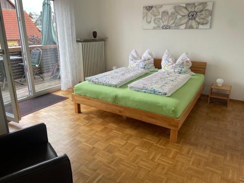 Un dormitorio con una cama verde con almohadas. en Ferienwohnungen Scheuring 1.OG, en Volkach