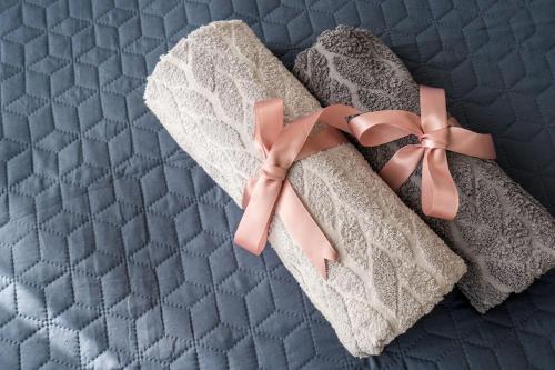um par de toalhas com um laço rosa numa cama em Twins Panorama Apartment em Gudauri
