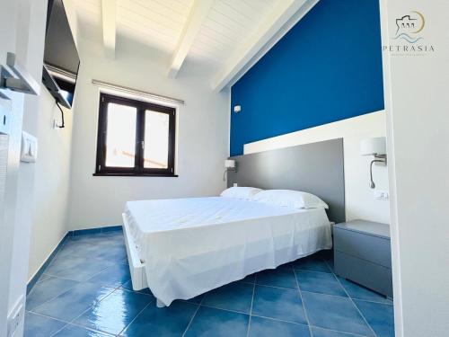 a blue and white bedroom with a bed and a window at Resort Petrasia in Villammare
