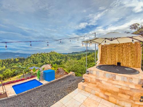 an outdoor spa with an umbrella and a swimming pool at Las Colinas Glamping in Turrialba