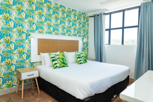 a bedroom with a large bed with green and white pillows at Precious Paradise Ushaka in Durban