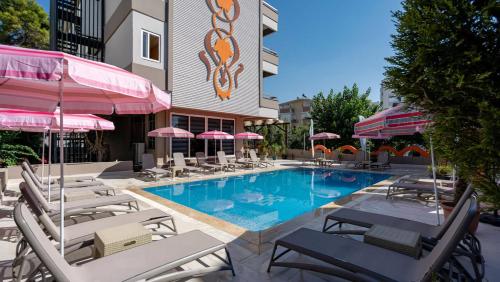 ein Pool mit Stühlen und Sonnenschirmen neben einem Hotel in der Unterkunft Lara Olympos Hotel in Antalya