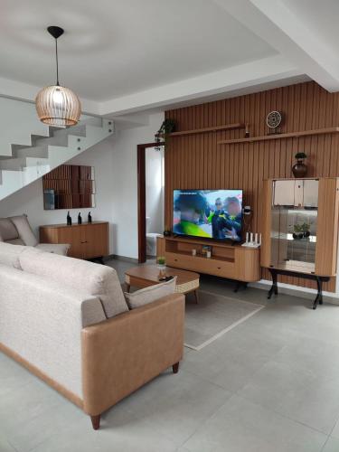 a living room with a couch and a flat screen tv at CASA DE PRAIA in Garopaba