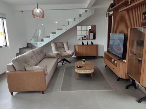 a living room with a couch and a tv and stairs at CASA DE PRAIA in Garopaba