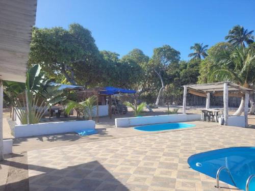 a patio with two blue trays and tables and trees at Casitas na Praia in Barra de Santo Antônio