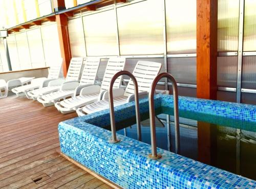 a pool on a cruise ship with white chairs at Akácliget Gyógy-és Strandfürdő in Karcag