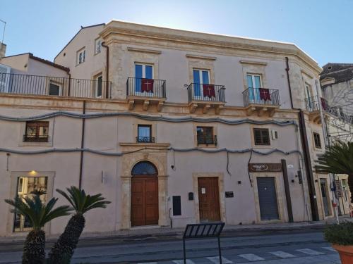 a large white building with balconies on a street at Casa Barú Scicli in Scicli