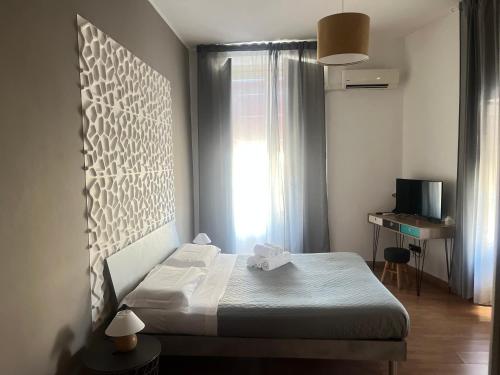 um pequeno quarto com uma cama e uma janela em B&B Stesicoro InHabit - GuestHouse City Center em Catânia