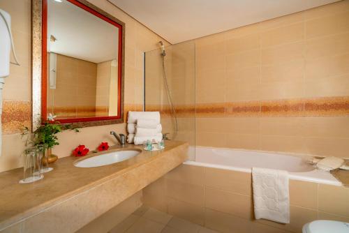 La salle de bains est pourvue d'un lavabo, d'une baignoire et d'un miroir. dans l'établissement Le Hammamet Hotel & SPA, à Hammamet