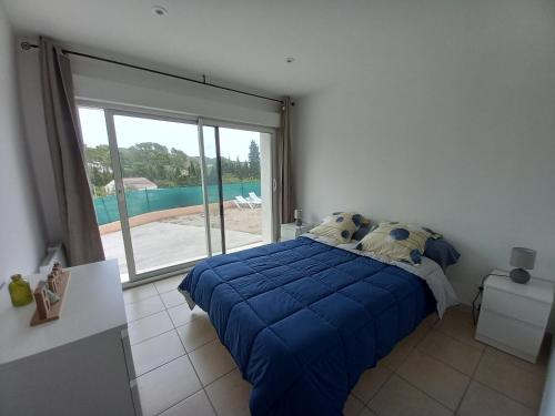une chambre avec un lit bleu et une grande fenêtre dans l'établissement la ciotat bas de villa, à La Ciotat
