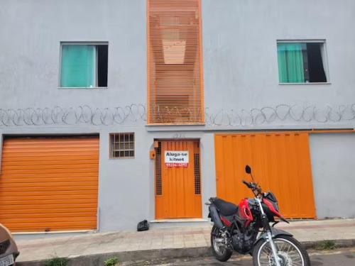 a motorcycle parked in front of a building with orange doors at Kitinet Central in Belo Horizonte