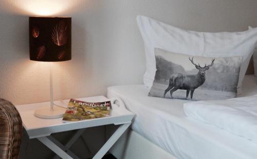a bed with a pillow with a deer on it next to a table at Landfein Big Country House in Winterberg