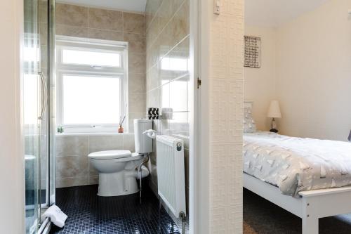 La salle de bains est pourvue de toilettes, d'un lavabo et d'un lit. dans l'établissement The Bell Lodge, à Sandown