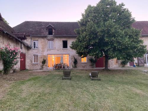 a house with two chairs and a tree in the yard at Gite tout confort - Vexin - Val d'Oise in Frémainville
