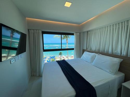 Apto Beira-mar vista piscinas naturais في بورتو دي غالينهاس: غرفة نوم بسرير مع اطلالة على الشاطئ