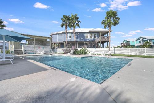 a swimming pool in front of a house with palm trees at The Blue Shell in Port Aransas