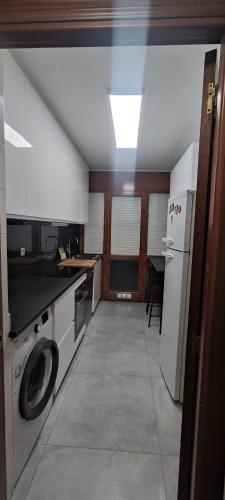 eine Küche mit einer Waschmaschine, einer Spüle und einem Kühlschrank in der Unterkunft Alojamiento Tierra del Ara in Boltaña