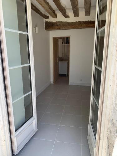 a hallway with glass doors and a tile floor at Gite tout confort - Vexin - Val d'Oise in Frémainville