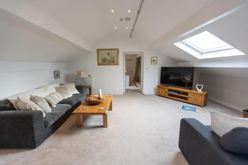 a living room with a couch and a tv at The Amazing Attik Apartment in Skipton