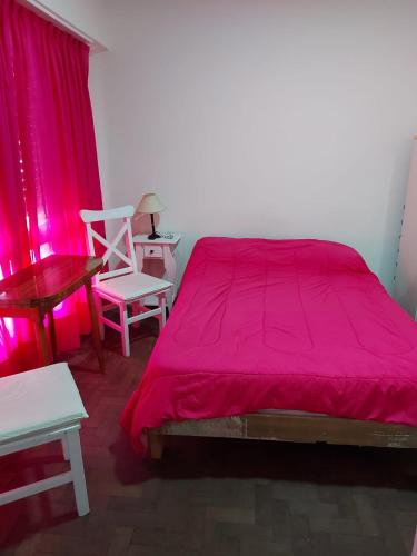 a bedroom with a red bed and two chairs at Depto casique 2pax in Necochea
