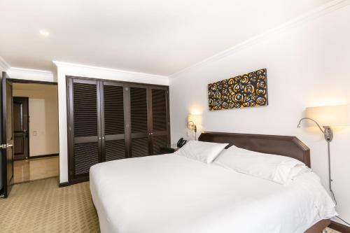 a bedroom with a white bed and a television at Hotel 101 Park House in Bogotá