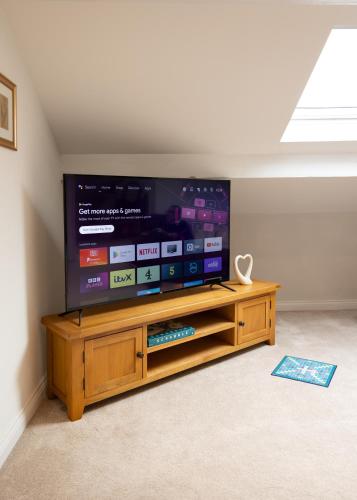 a large flat screen tv sitting on a wooden entertainment center at The Amazing Attik Apartment in Skipton