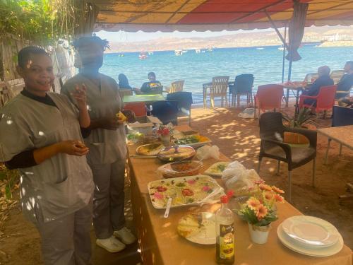 two men standing in front of a table with food at Al-Amer Hostel 2 in Aqaba