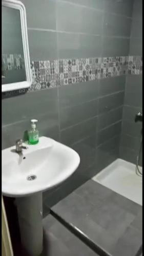 a bathroom with a white sink and a shower at Appartement à ALHOCEIMA in Al Hoceïma